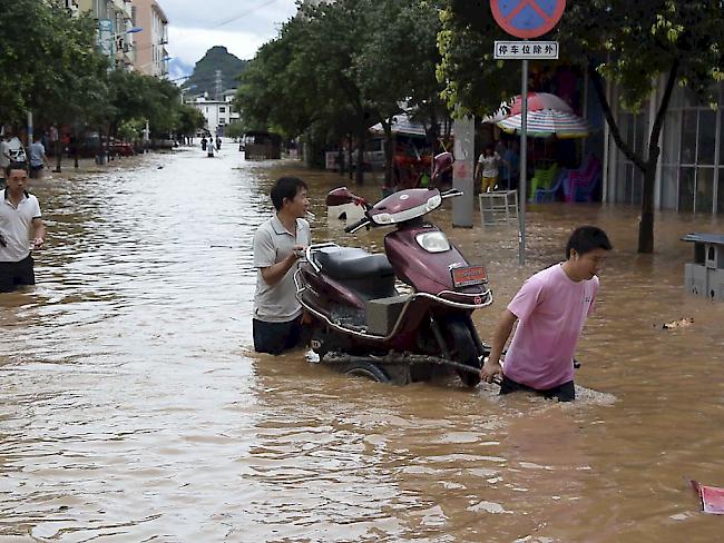 Bewohner der überschwemmten chinesischen Stadt Guiyang versuchen, einen Motorroller ans Trockene zu bringen (Archiv)