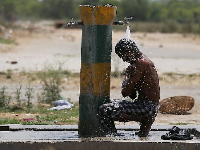 Ein indischer Arbeiter kühlt sich unter einem Wasserhahn in Amritsar. Wegen einer Hitzewelle starben in Indien bisher mindestens 750 Menschen.
